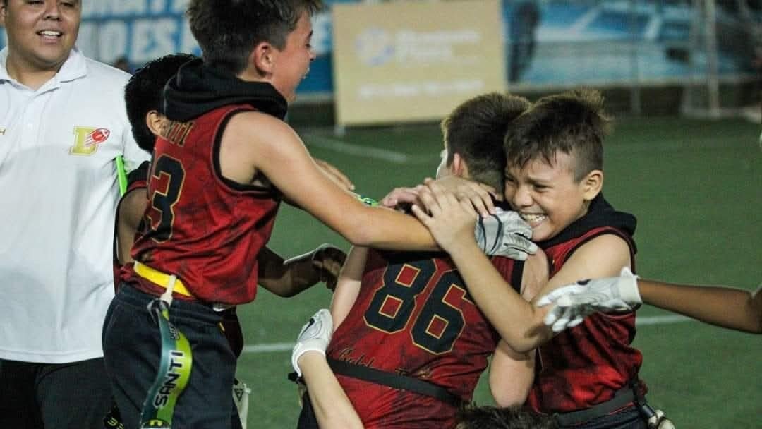 Jugadores de Dorados Mérida U12 celebrando touchdown con abrazos y sonrisas en torneo de flag football